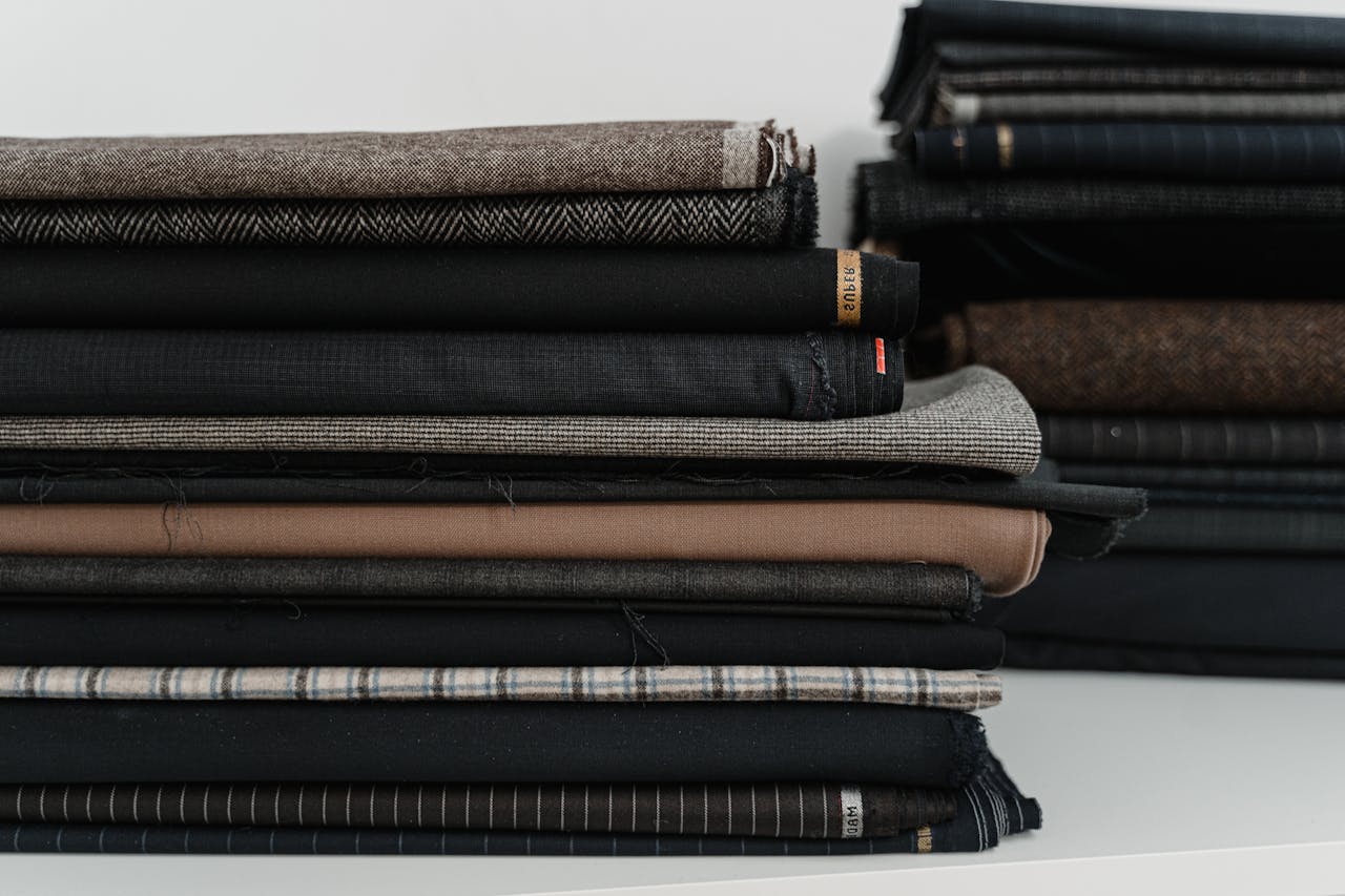 A neatly arranged pile of diverse fabrics, ideal for a fashion designer or tailor's workshop.